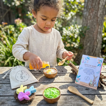 Child playing with sensory materials on a wooden table outdoors